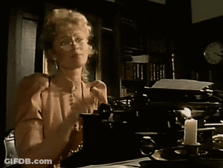 Woman Sitting At Table With Typewriter And Candle GIF