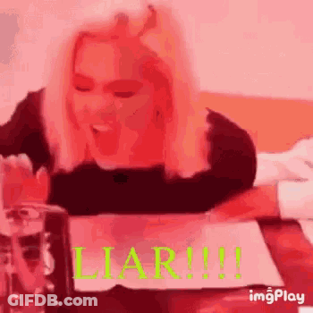 Woman Sitting At Table With Water And Liar Sign GIF