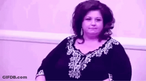Woman Sitting By Purple Wall In Purple White Shirt GIF