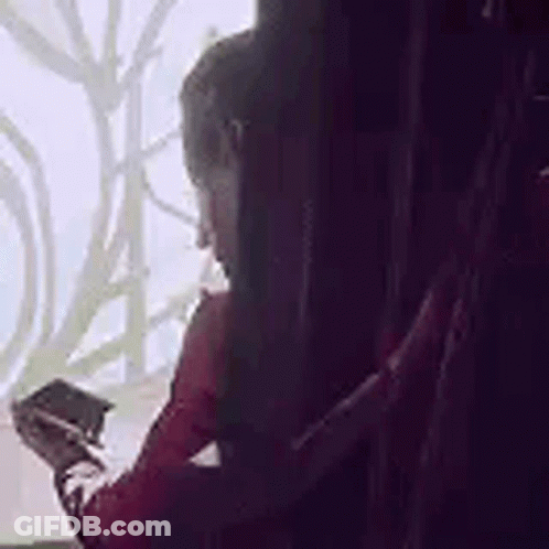 Woman Sitting By Window Holding Pen And Phone GIF