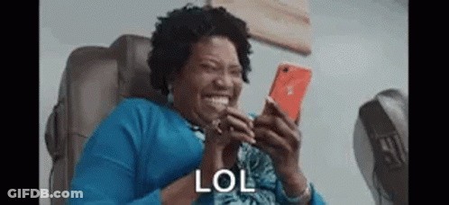 Woman Sitting In Chair Laughing At Phone GIF