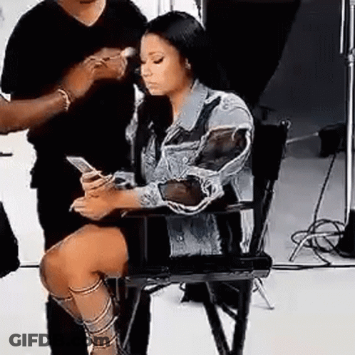Woman Sitting In Chair Looking At Phone While Man Brushes Her Hair GIF