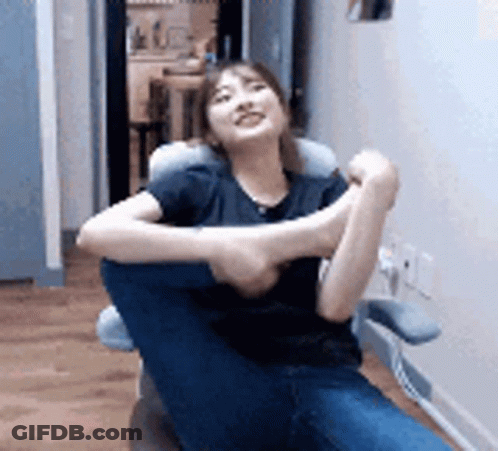 Woman Sitting In Chair With Legs Crossed And Pillow GIF