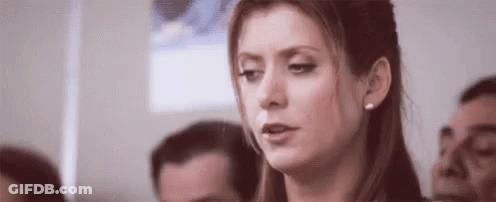 Woman Sitting In Crowd Looking At Camera GIF