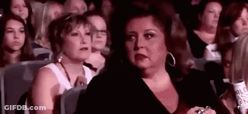 Woman Sitting In Crowd Watching Performance GIF