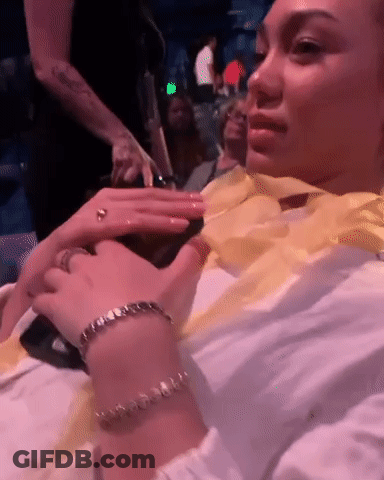 Woman Sitting In Crowded Room With Bracelet And Ring GIF