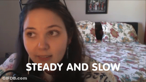 Woman Sitting In Front Of Bed Saying Steady And Slow GIF