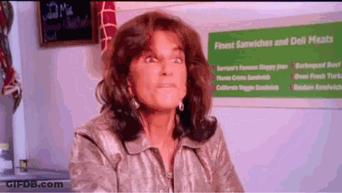 Woman Sitting In Front Of Finest Sandwiches And Deli Meats Sign GIF
