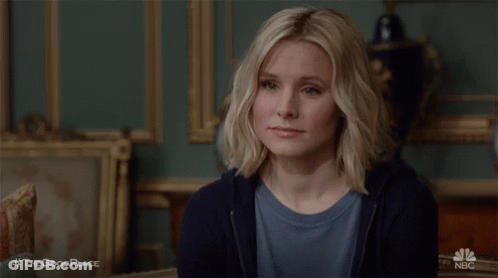 Woman Sitting In Room With Painting Looking At Camera GIF