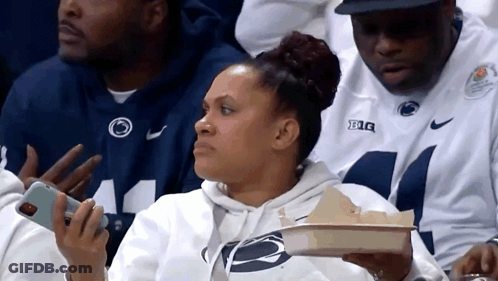 Woman Sitting In Stands Holding Tray Of Food And Phone GIF
