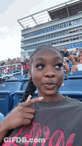 Woman Sitting In Stands Pointing At Herself GIF