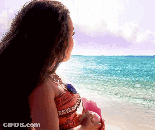 Woman Sitting On Beach Holding Seashell GIF