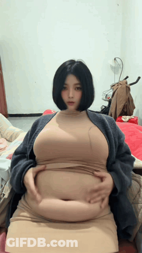 Woman Sitting On Bed Holding Belly GIF
