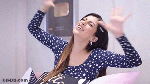 Woman Sitting On Bed Smiling Arms Outstretched GIF