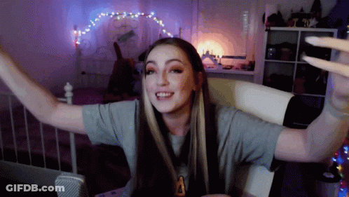 Woman Sitting On Bed With Arms Outstretched And Letter A On Shirt GIF