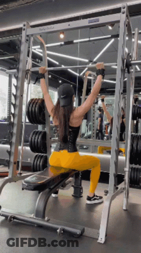 Woman Sitting On Bench In Gym Holding Barbell Overhead GIF