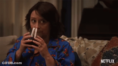 Woman Sitting On Couch Drinking With Netflix Logo GIF