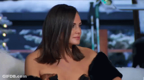 Woman Sitting On Couch In Fur Coat And Strapless Top GIF
