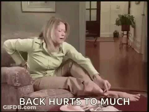 Woman Sitting On Couch In Pain Saying Back Hurts Too Much GIF
