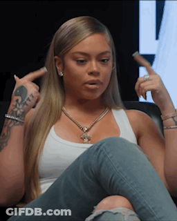 Woman Sitting On Couch In White Tank Top And Blue Jeans GIF