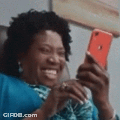 Woman Sitting On Couch Smiling At Phone GIF