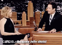 Woman Sitting On Couch Talking To Man In Suit Saying Do Some Jello Shots GIF