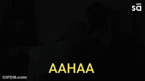 Woman Sitting On Couch With Aahaa In Yellow Letters GIF