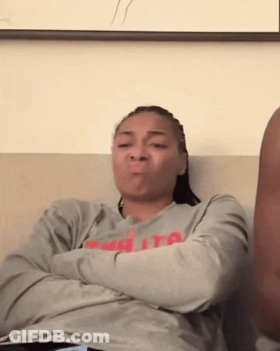 Woman Sitting On Couch With Arms Crossed Wearing Ita Shirt GIF