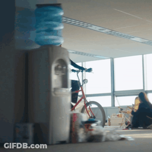 Woman Sitting On Floor By Bicycle And Water Cooler GIF