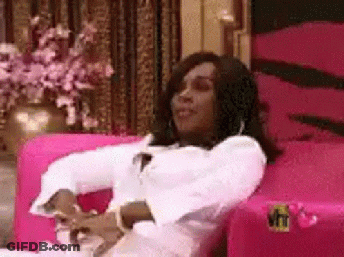 Woman Sitting On Pink Couch With Arms Crossed GIF