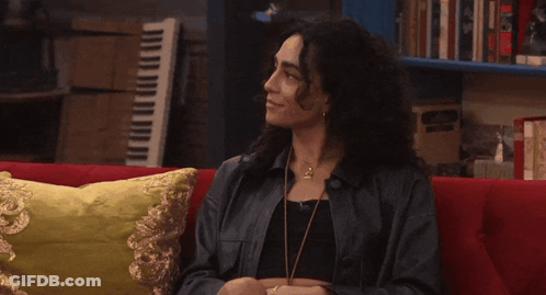 Woman Sitting On Red Couch In Front Of Piano GIF