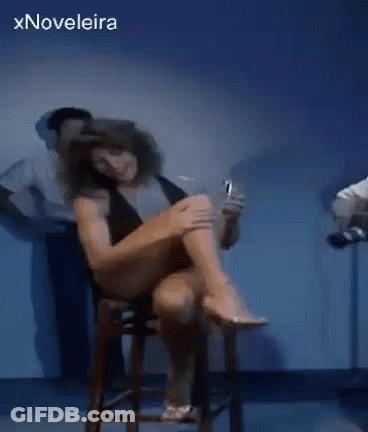 Woman Sitting On Stool With Legs Crossed Holding Alcohol GIF