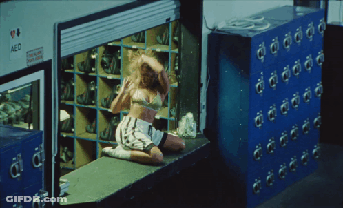 Woman Sitting On Window Sill In Front Of AED Locker GIF