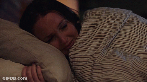 Woman Sleeping Under Striped Blanket GIF