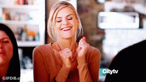 Woman Smiling Hands In Air At Table GIF