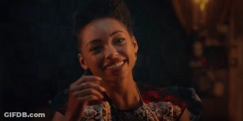 Woman Smiling Holding Glass Of Wine In Dark Room GIF