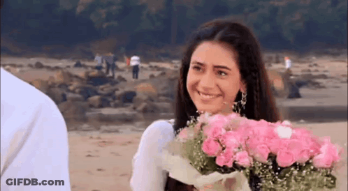 Woman Smiling Holding Pink Roses On Beach GIF