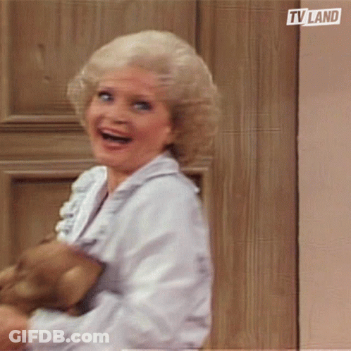 Woman Smiling Holding Teddy Bear In Front Of TV Land Door GIF