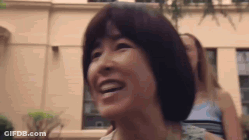 Woman Smiling In Front Of Building With Another Woman Looking On GIF