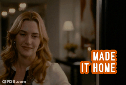Woman Smiling In Front Of Made It Home Sign GIF