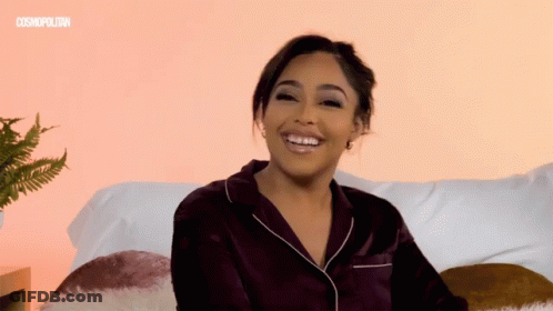 Woman Smiling In Front Of Pink Wall With Cosmopolitan GIF