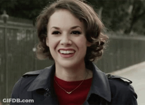 Woman Smiling In Trench Coat And Necklace GIF