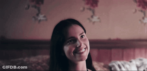 Woman Smiling On Bed In Dark Room GIF