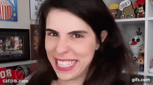 Woman Smiling With Shelf Of Toys GIF