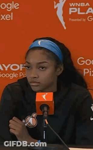 Woman Speaking Into Microphone In Front Of WNBA Sign GIF