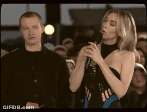 Woman Speaking Into Microphone With Man Behind GIF