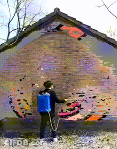 Woman Spraying Paint On Brick Wall With Blue Backpack GIF