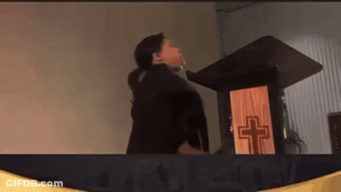 Woman Standing At Podium With Wooden Cross GIF