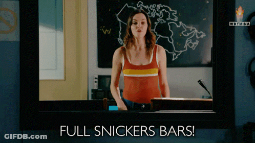 Woman Standing Before Full Snickers Bars GIF