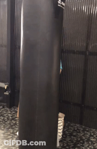 Woman Standing Behind Punching Bag That Says Isan GIF